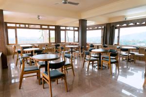 een restaurant met tafels, stoelen en ramen bij Baviecoresort in Ba Vì