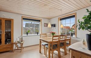 a dining room with a table and chairs and windows at Nice Home In Thyborøn With Wifi in Thyborøn
