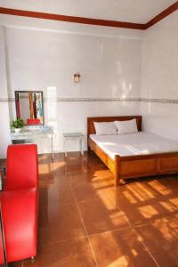 Un dormitorio con una cama y una silla roja. en Vườn Dừa Cam Bình 2, en Vĩnh Thạnh 37 fotos más