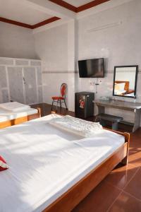 Un dormitorio con una cama, un escritorio y un televisor. en Vườn Dừa Cam Bình 2, en Vĩnh Thạnh