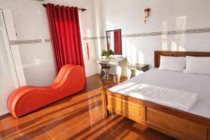 Un dormitorio con una cama y una silla roja. en Vườn Dừa Cam Bình 2, en Vĩnh Thạnh
