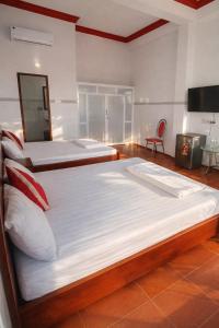 Un dormitorio con dos camas y un televisor. en Vườn Dừa Cam Bình 2, en Vĩnh Thạnh