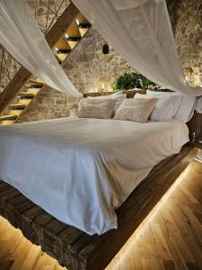een slaapkamer met een wit bed en een stenen muur bij La Nuit d'Amélie 2 in Norma