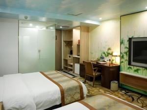 Un dormitorio con una cama, un escritorio y un televisor. en Golden Central Hotel Shenzhen, en Shenzhen