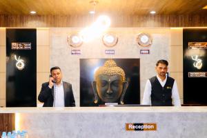 インドールにあるTHE CLAN HOTEL - VIJAY NAGAR Indoreのカウンターの後ろに彫像とともに立っている3人の男性