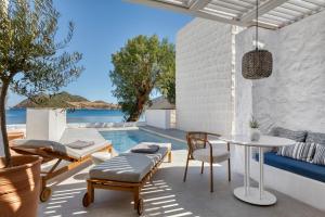 eine Terrasse mit Tisch und Stühlen und einem Pool in der Unterkunft Patmos Aktis, a Luxury Collection Resort & Spa, Greece in Patmos