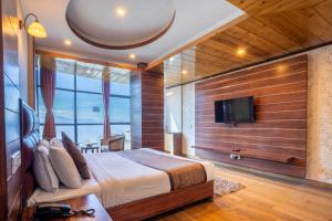 een slaapkamer met een bed en een flatscreen-tv bij Yashshree Jai Hotel & Banquet in Darjeeling