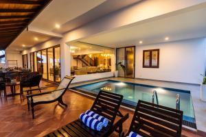 una piscina en una casa con sillas y mesa en The Beach Home, en Galle