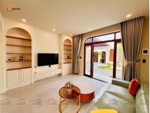 een woonkamer met een tv en een bank bij Bi Home in Phú Mỹ