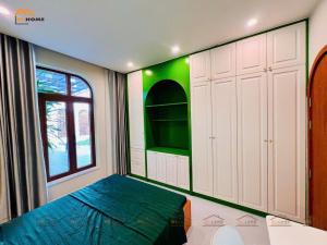 a bedroom with a bed and a green wall at Bi Homestay Phú Mỹ in Phú Mỹ
