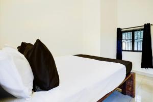 a white bed in a room with a window at Hotel O by OYO Shoreline Horizon Hideaway in Anjuna