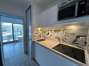 una cucina con lavandino e forno a microonde sopra un bancone di HYEDHI Studio pour 4 personnes avec vue mer sur le port d'Hyères a Hyères