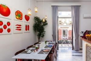 a dining room with a table with chairs and paintings of tomatoes at Palazzo Starace in Sorrento