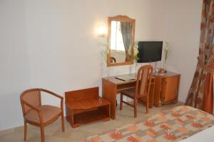 Habitación con escritorio, sillas y TV. en Hotel la princesse en Túnez