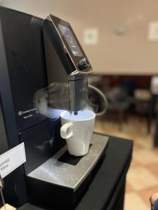 Una cafetera está preparando una taza de café. en Parkhotel Terezín, en Terezín