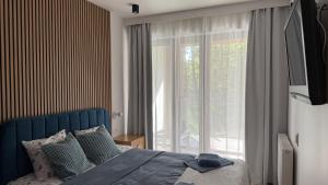 een slaapkamer met een bed en een groot raam bij Sea&Forest Międzyzdroje Amber Suite in Międzyzdroje