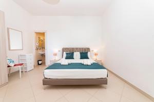 a white bedroom with a large bed with blue pillows at Mama Bed in Porto Cesareo