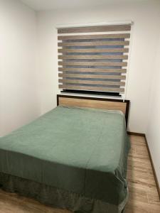 una camera da letto con un letto verde e una finestra di Atostogų namelis "Neda" a Palanga