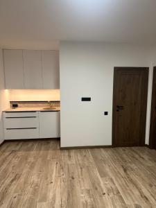 una cucina vuota con mobili bianchi e una porta di legno di Atostogų namelis "Neda" a Palanga Altre 5 foto