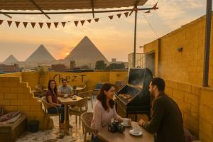 a group of people sitting at tables on a patio with pyramids at Chez l'ami hotel in Cairo