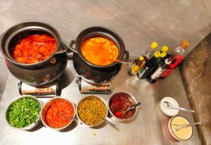 two pots of food on a counter with bowls of spices at 柯凡酒店-About 3 kilometers from the East Gate of Zhangjiajie Forest Park, English service, free recommended travel routes, ticket purchase in Zhangjiajie +38 photos