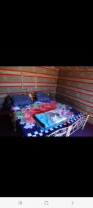 Una cama con una manta colorida encima. en Wadi rum view camp, en Wadi Rum