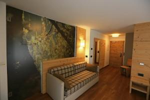 a couch against a wall with a large painting at Hotel San Giovanni in Vigo di Fassa