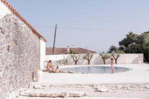een groep mensen die rond een zwembad zitten bij Casa d'Aire in Porto de Mós +5 foto's