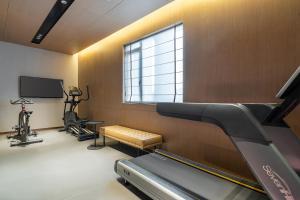 une salle de sport avec tapis roulant et appareils de musculation et une fenêtre dans l'établissement eLong Hotel Suzhou Guanqian Street, à Suzhou