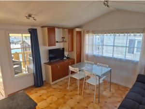 ein Wohnzimmer mit Tisch und Stühlen und einem Fernseher in der Unterkunft Mobil-home camping Le Ptit Rio in Noyelles-sur-Mer
