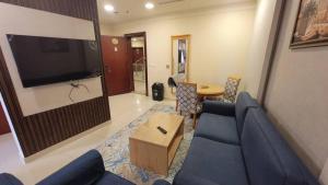 达曼صفاء المسكن的客厅配有蓝色的沙发和平面电视。