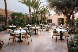 een patio met tafels en stoelen en palmbomen bij Hotel Boutique Petit París in Port de Pollença +3 foto's