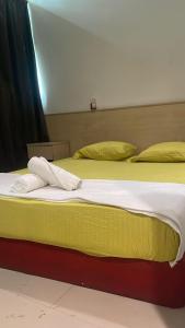 Batu Caves Paradise Hotel في بانيا إليجا: سريرين مع أغطية ومخدات صفراء وبيضاء +17 صورة