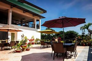Puerto PrincesaにあるIpil Suites Puerto Princesaのテーブルと椅子、パラソルのあるパティオ