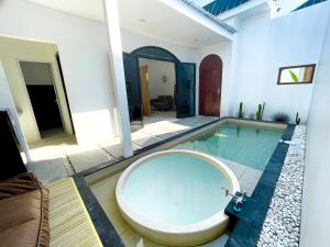 ein Badezimmer mit einer Badewanne und einem Pool in der Unterkunft Oasis Montana Jogja in Ngemplak