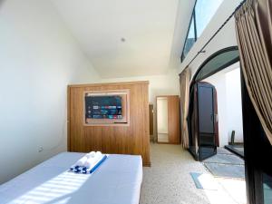 ein Schlafzimmer mit einem Bett und einem Fernseher an der Wand in der Unterkunft Oasis Montana Jogja in Ngemplak