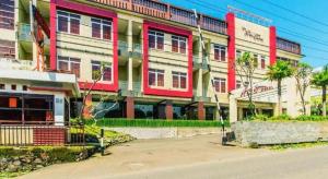 チウィデイにあるAlbis Hotelのヤシの木が目の前に広がる赤と白の建物