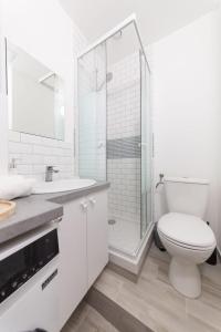 a white bathroom with a toilet and a shower at Le Petit nid cocooning - Studio chaleureux et élégant in Aubervilliers