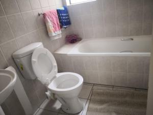 a bathroom with a toilet and a bath tub at Duplex in Tableview in Cape Town +9 photos