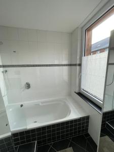 eine weiße Badewanne in einem Badezimmer mit Fenster in der Unterkunft Stadtwohnung in Groß-Umstadt in Groß-Umstadt + 14 Fotos