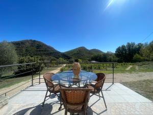 ein Glastisch mit Stühlen und einer Vase auf einer Terrasse in der Unterkunft Charmant Duplex à la campagne in Riventosa