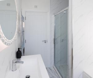 a white bathroom with a shower and a sink at The Views Retreat in Newcastle +94 photos