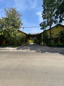 an empty street with a yellow building and trees at Maam Guesthouse in Phnom Penh
