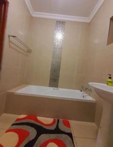 een badkamer met een ligbad en een wastafel bij Lovicc Guest house mafikeng in Mahikeng