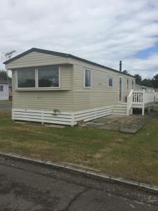 a small yellow house with a porch and a yard at Lovely 3 Bed Caravan, Milford on Sea in Milford on Sea