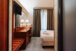 Habitación de hotel con escritorio, cama y espejo en Hotel Chelsea, en Turín
