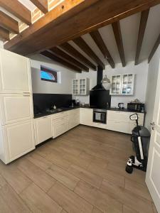 a large kitchen with white cabinets and a wooden ceiling at havre de paix a la Sologne in Veilleins