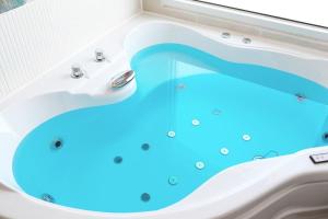 ein Badezimmer mit einer Badewanne mit blauem Wasser in der Unterkunft Gangneung Maison de Rose in Gangneung