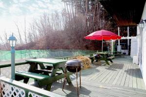 eine Terrasse mit Picknicktischen und einem roten Regenschirm in der Unterkunft Gangneung Maison de Rose in Gangneung