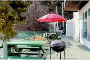 ein Picknicktisch mit einem Grill und einem roten Sonnenschirm in der Unterkunft Gangneung Maison de Rose in Gangneung + 66 Fotos